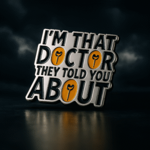 Metal brooch with bold typography reading “I’m that doctor they told you about,” with yellow accent O’s shaped like stethoscope heads.