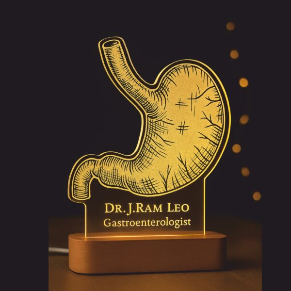 Customized LED night lamp with a glowing anatomical stomach design, engraved with “Dr. J. Ram Leo – Gastroenterologist,” placed on a wooden base in a hospital hallway.