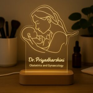 Personalized LED night lamp featuring a glowing line art illustration of a mother holding her newborn, engraved with “Dr. Priyadharshini – Obstetrics and Gynaecology,” displayed on a wooden base.