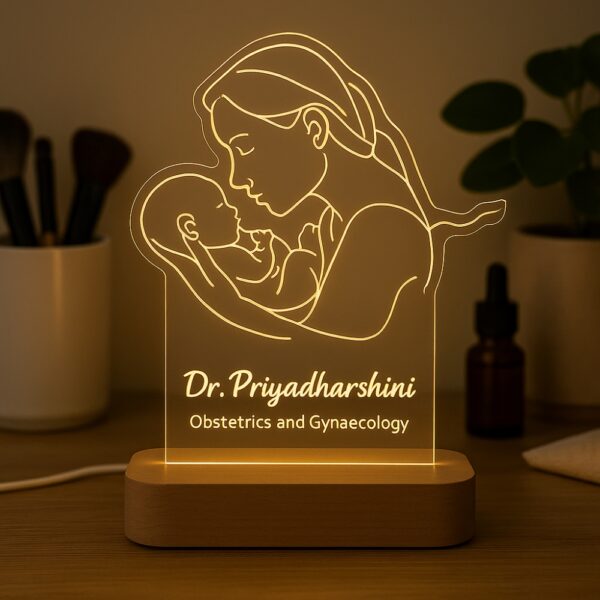 Personalized LED night lamp featuring a glowing line art illustration of a mother holding her newborn, engraved with “Dr. Priyadharshini – Obstetrics and Gynaecology,” displayed on a wooden base.