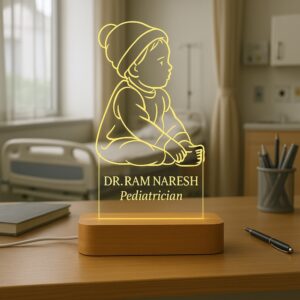 LED night lamp featuring an engraved outline of a baby sitting with a beanie, with the name “Dr. Ram Naresh – Pediatrician” glowing warmly on a wooden base in a hospital setting.