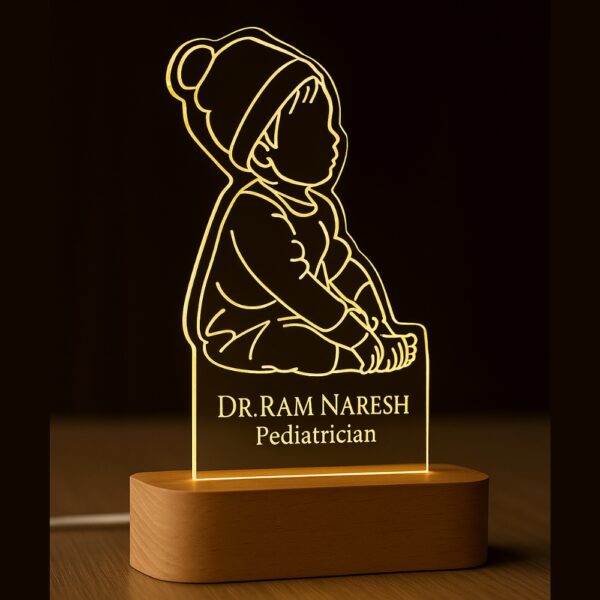 LED night lamp featuring an engraved outline of a baby sitting with a beanie, with the name “Dr. Ram Naresh – Pediatrician” glowing warmly on a wooden base in a hospital setting.