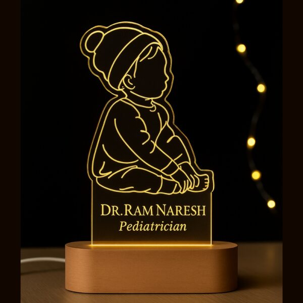 LED night lamp featuring an engraved outline of a baby sitting with a beanie, with the name “Dr. Ram Naresh – Pediatrician” glowing warmly on a wooden base in a hospital setting.
