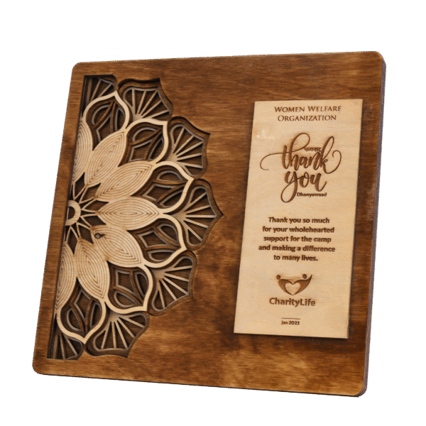 Intricately carved wooden plaque with mandala design and engraved appreciation message for medical camp contribution.