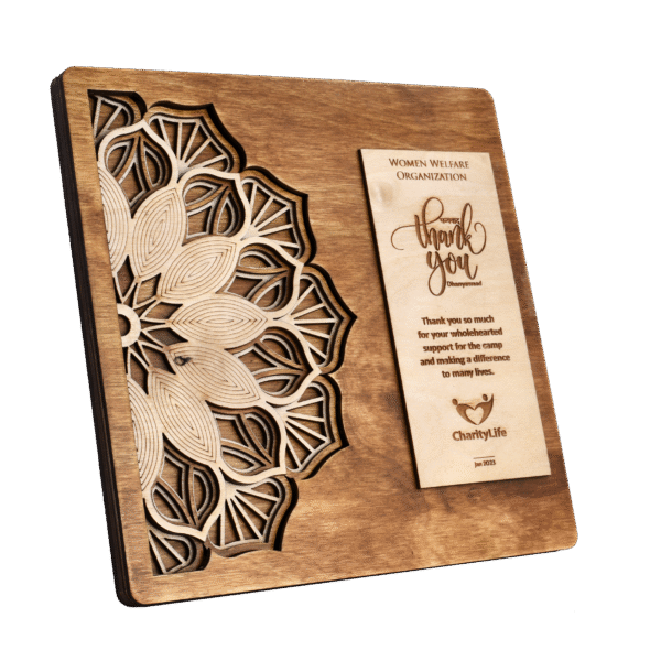 Intricately carved wooden plaque with mandala design and engraved appreciation message for medical camp contribution.