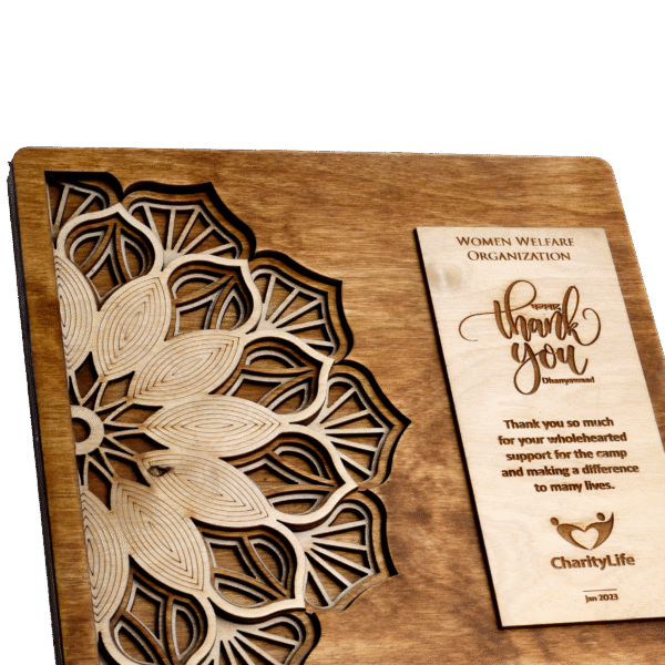Intricately carved wooden plaque with mandala design and engraved appreciation message for medical camp contribution.