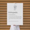 Line art orthopedic wall poster with a knee joint sketch and a humorous definition for an orthopedic doctor.