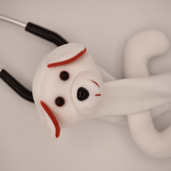 White puppy-themed stethoscope skin with floppy ears and stitched eyes wrapped around a stethoscope.